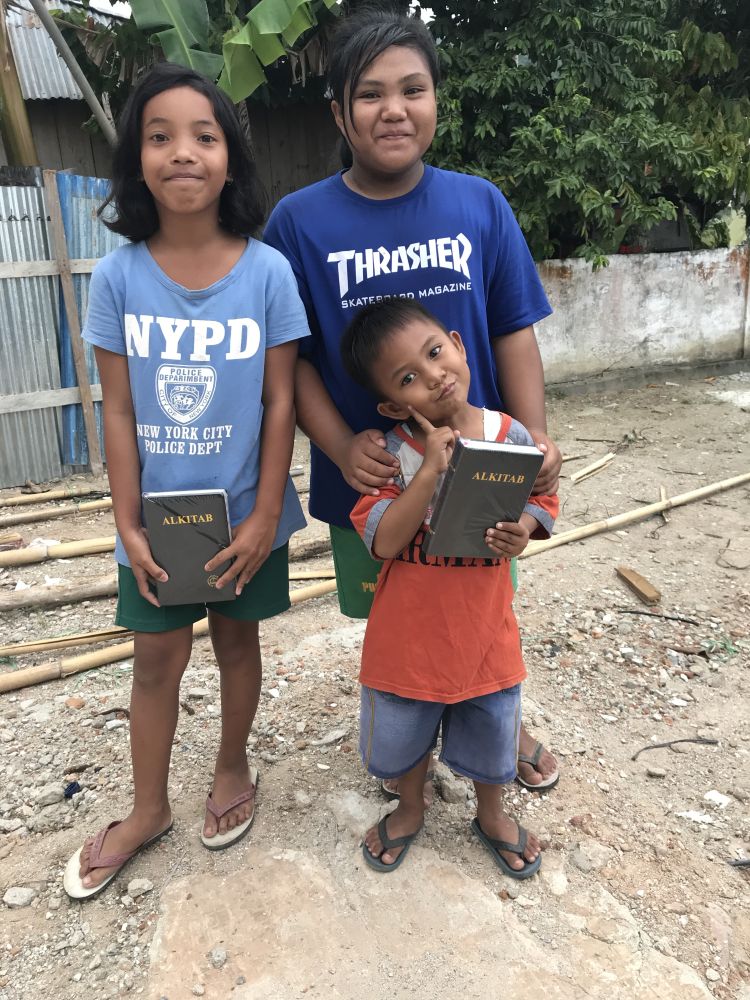 Children joyfully receive Bibles during a Christmas Care pack distribution in Indonesia.