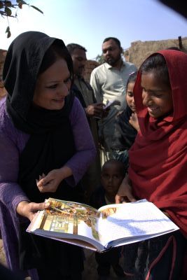 A girl receiving a children's Bible from a Pakistani gospel worker in early 2026.