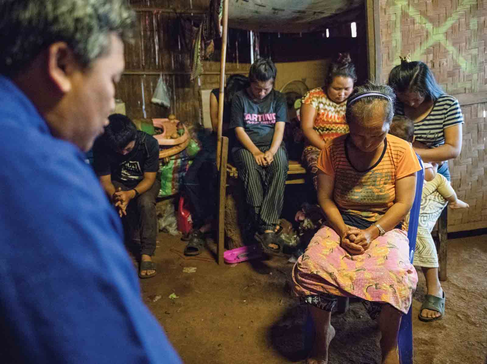 A pastor prays with members of a Southeast Asian tribal group at home.