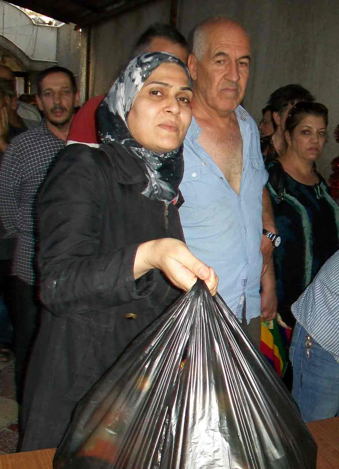A Syrian woman collects food aid from a church at a previous distribution.