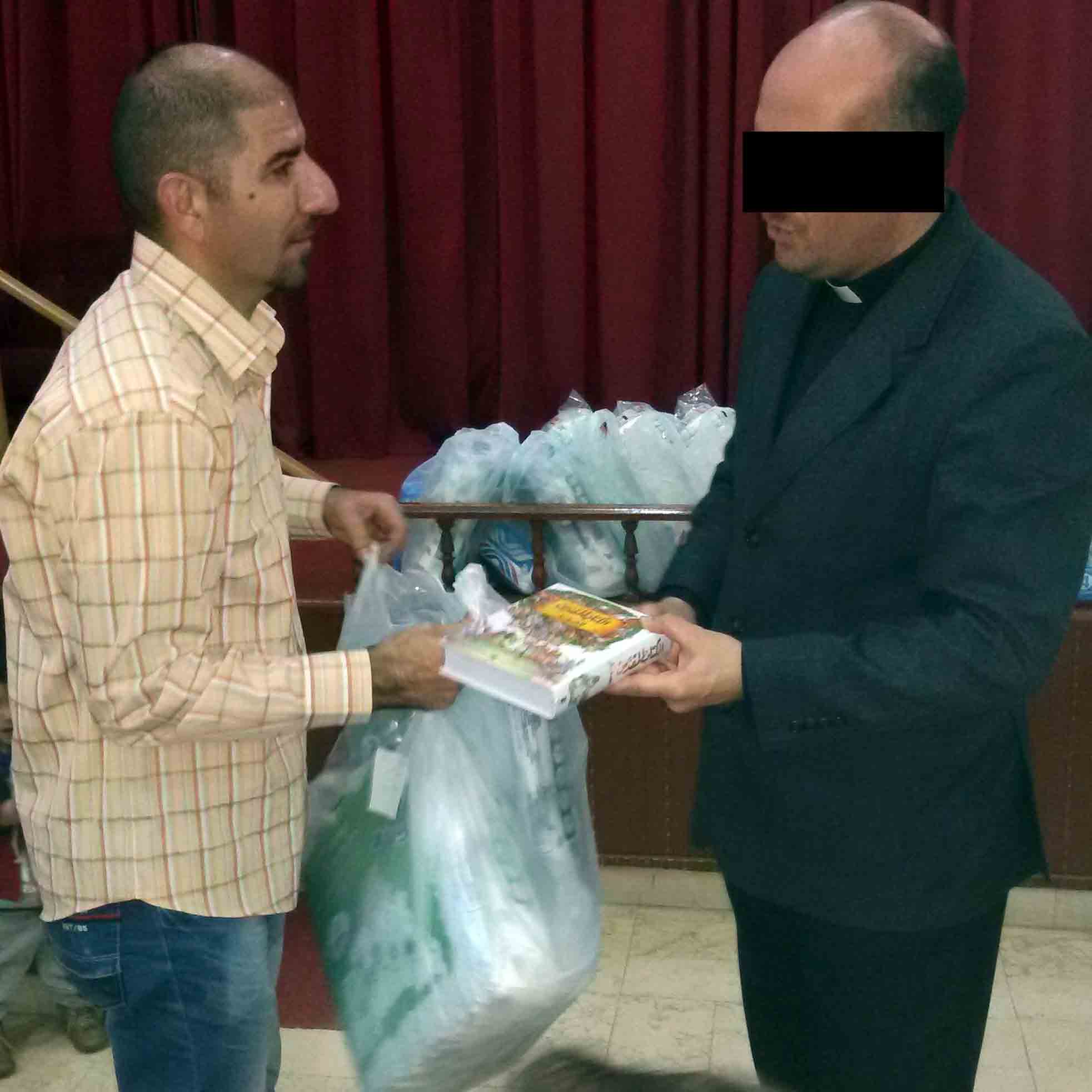 A pastor distributes a Bible along with food aid to a refugee.