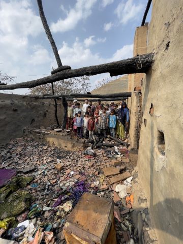 A family stands in the remains of their burned home.
