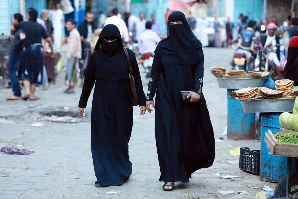 Two Muslim women walking down a street in Yemen.