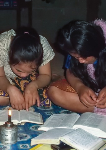 Two young Lao girls read Bibles