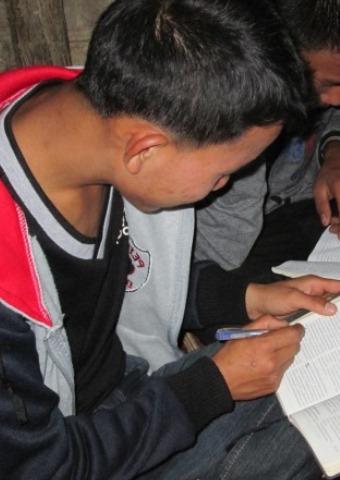 A young man from Laos studies the Bible with several others where the Christians are often persecuted for their faith by their families.