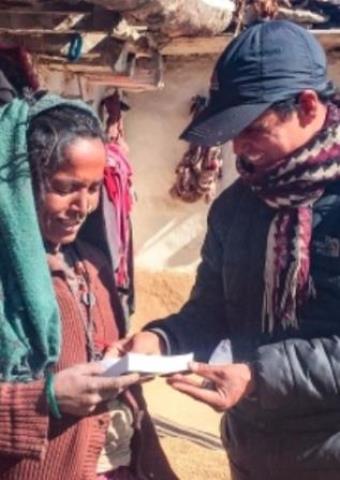 A front-line worker giving a Nepali woman a Bible.