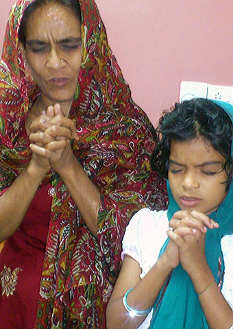 Vani and her daughter pray together after her recent release from prison.